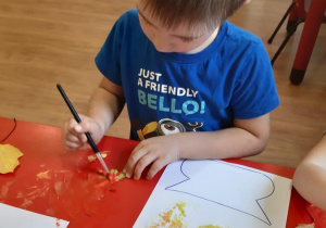 Mateusz maluje liść farbą.